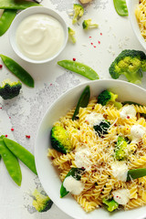 Pasta with green vegetables broccoli, Mange tout and creamy sauce in white plate