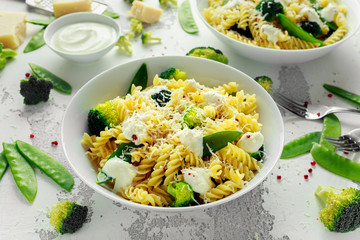 Pasta with green vegetables broccoli, Mange tout and creamy sauce in white plate