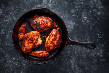 Cooked chicken fillets, breast supremes in rustic cast iron skillet.