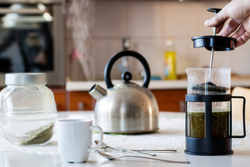 Morning yerba tea. Tasty tea brewed in cafetiere on the kitchen table.