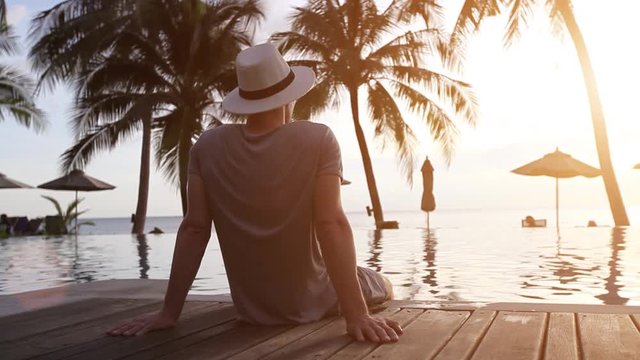 relaxation on the beach, young man enjoying beautiful sunset in luxury hotel, vacation
