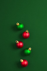 Christmas ornaments, green and red on a green background. Top view. Copy space