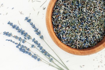Dried herb of lavender blue blossom in wooden bowl, top view closeup.