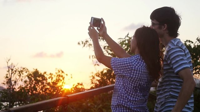 Romantic couple taking selfie video by sunset during vacation. Slow motion. Woman and man taking cell phone photos. 1920x1080