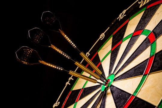 Sisal Dartboard With Three Darts In A Bullseye On A Black Background