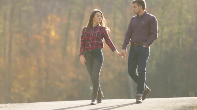 A loving couple walks in the autumn in the park. A love story on a sunny autumn day. lake and bringe .