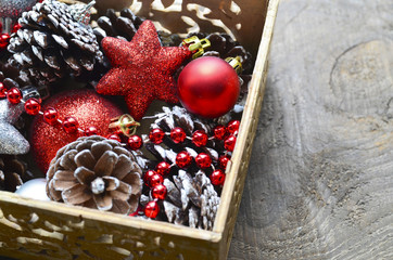 Christmas tree decoration: red and silver shiny balls,stars and pine cones in a vintage wooden box.Prepare for Christmas Eve or New Year winter holidays.Selective focus.