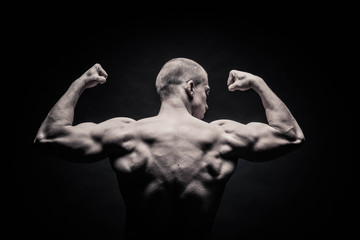 Fototapeta na wymiar portrait of a male bodybuilder on a black background isolated. monochrome. The concept of a photo of competing sports, health, fitness