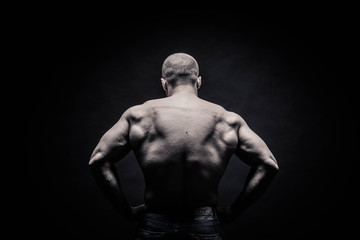 Obraz na płótnie Canvas portrait of a male bodybuilder on a black background isolated. monochrome. The concept of a photo of competing sports, health, fitness