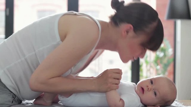 Mother gently kissing baby on the changing table at home
