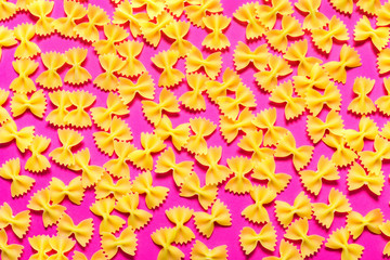 Heap of pasta farfalle on pink background