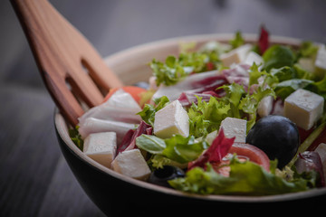 Greek salad and vegetables on the black wood table 