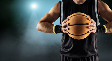 Fototapeta premium Basketball ball in a male hands, player in black with orange spo