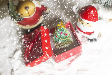Fototapeta na wymiar Miniature Christmas Santa cros and Tree on snow over blurred bokeh background,Decoration Image for Christmas Holiday and Happy New Year Gift box Celebration concept.