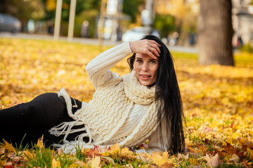 portrait of a beautiful young girl in fashionable business clothes walking along the autumn park, catching the falling leaves