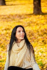 portrait of a beautiful young girl in fashionable business clothes walking along the autumn park, catching the falling leaves