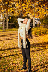 Fototapeta premium portrait of a beautiful young girl in fashionable business clothes walking along the autumn park, catching the falling leaves