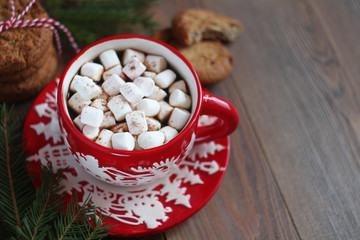Red Christmas mug of coffee and marshmallows and cookies on the wooden table