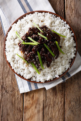 Mongolian beef with sauce and garnish of rice. Vertical top view