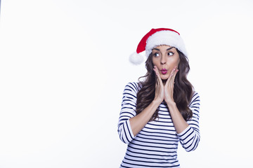 How is this possible? Attractive young smiling woman in santa hat posing on white background isolated.