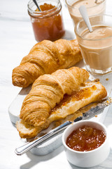 croissants with orange jam and coffee with milk for breakfast, vertical top view