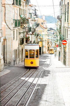 Street view with famous yellow funicular tram in Lisbon during the sunny day in Portugal