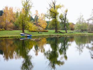 Fototapeta na wymiar Autumn landscape with colorful forest, lake, reflection and a boat