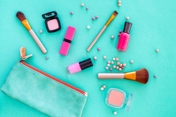 Content of cosmetic bag. Lipstick, eye shadows, nail polish, rouge, brushes for makeup on blue background top view