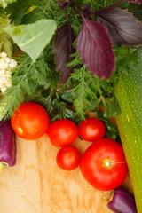Harvest of fresh vegetables on a wooden background, in garden background. Top view. Garlic, beet, zucchini, kohlrabi, cauliflower, pepper, tomatoes, potatoes, basil, cucumber, dill.