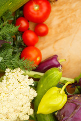 Harvest of fresh vegetables on a wooden background, in garden background. Top view. Garlic, beet, zucchini, kohlrabi, cauliflower, pepper, tomatoes, potatoes, basil, cucumber, dill.
