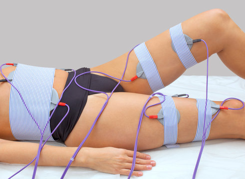 The procedure of myostimulation on the legs and buttocks of a woman in a beauty salon. Caring for the body, reducing excess weight.