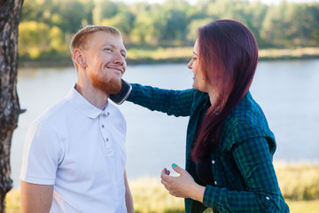 Young loving married couple on the river bank, man and beautiful girl on nature in summer