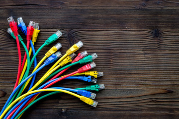 Network wires assorted colors with tips on dark wooden background top view copyspace