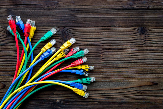 Network wires assorted colors with tips on dark wooden background top view copyspace