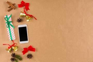Phone and Christmas decorations on craft paper background, top view, flat lay.
