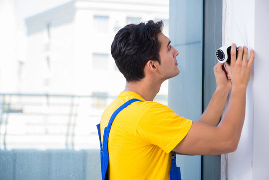 Contractor installing surveillance CCTV cameras in office