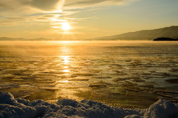 Ice floes floating on the fog water in the lake Baikal. Sunset