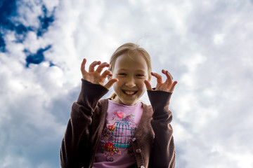 Girl laughs and scares against the blue sky