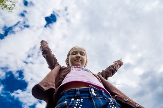 The Girl Is Standing With Her Hands Up Against The Sky - A View From Below