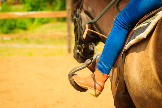 Woman Foot In Stirrup On Horse Saddle