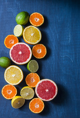 Assortment of citrus fruits on a blue background, top view. Oranges, grapefruit, tangerine, lime, lemon - organic fruits, vegetarian healthy food concept