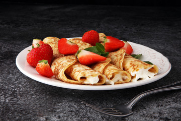 Crepes with jam, berries and sugar powder. Homemade pancakes, delicious breakfast.