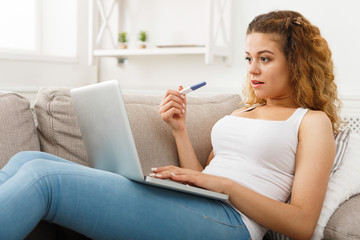 Woman browsing on laptop with pregnancy test