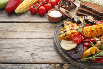Grilled vegetable on brown cutting board with salt, pepper and bread