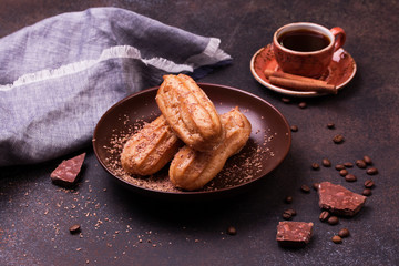 Chocolate eclair and coffee cup on dark background