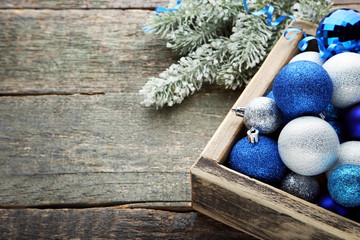 Blue and silver christmas baubles in crate with fir-tree branches