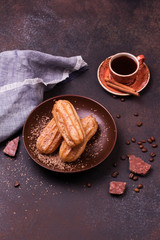 Chocolate eclair and coffee cup on dark background
