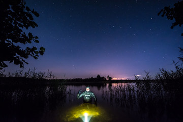 Fisherman in water at night. Night underwater fishing.