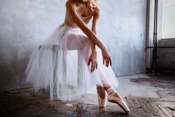 Fototapeta premium Młoda i szczupła tancerka baletowa pozuje w stylowym studio z dużymi oknami