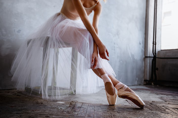 Young and slim ballet dancer is posing in a stylish studio with big windows - obrazy, fototapety, plakaty